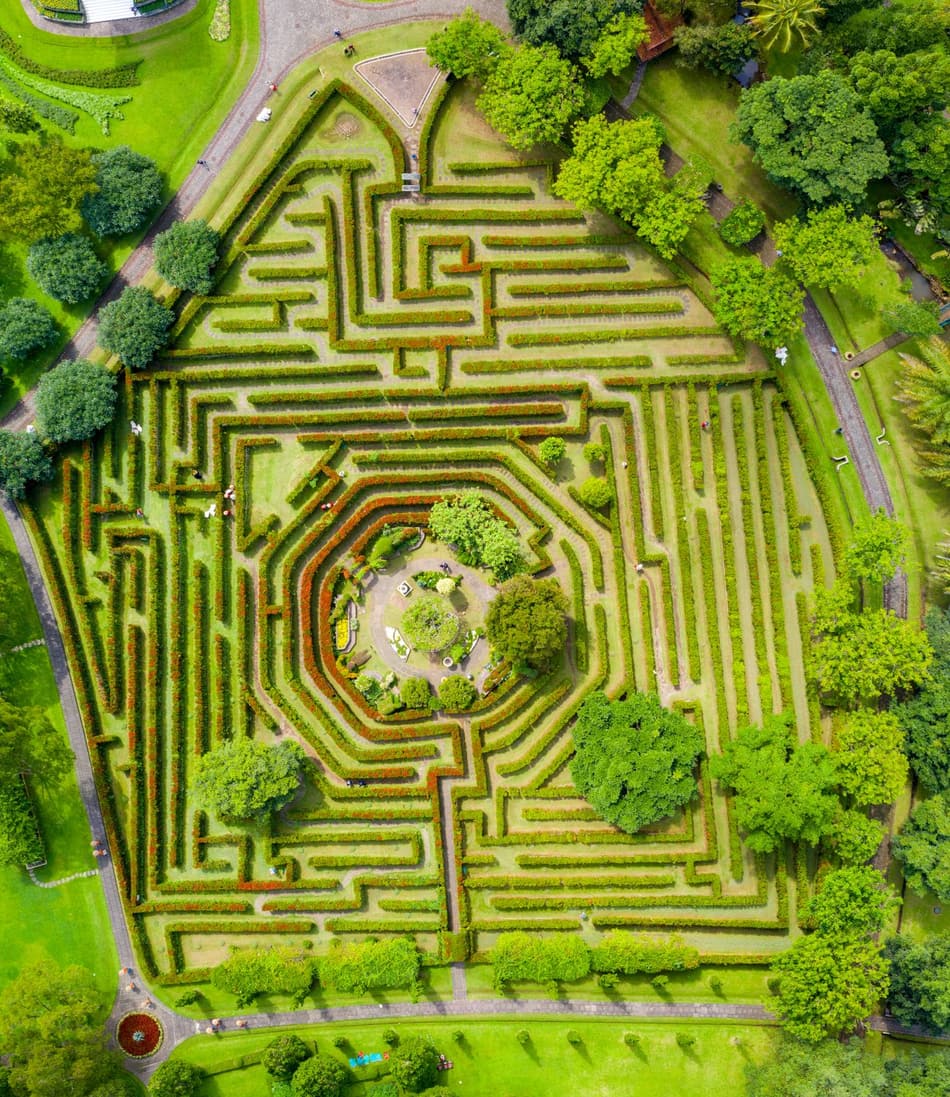 Vue aérienne d'un labyrinthe de haies vertes, dont les allées s'entrecroisent sans qu'on puisse suivre un chemin du regard