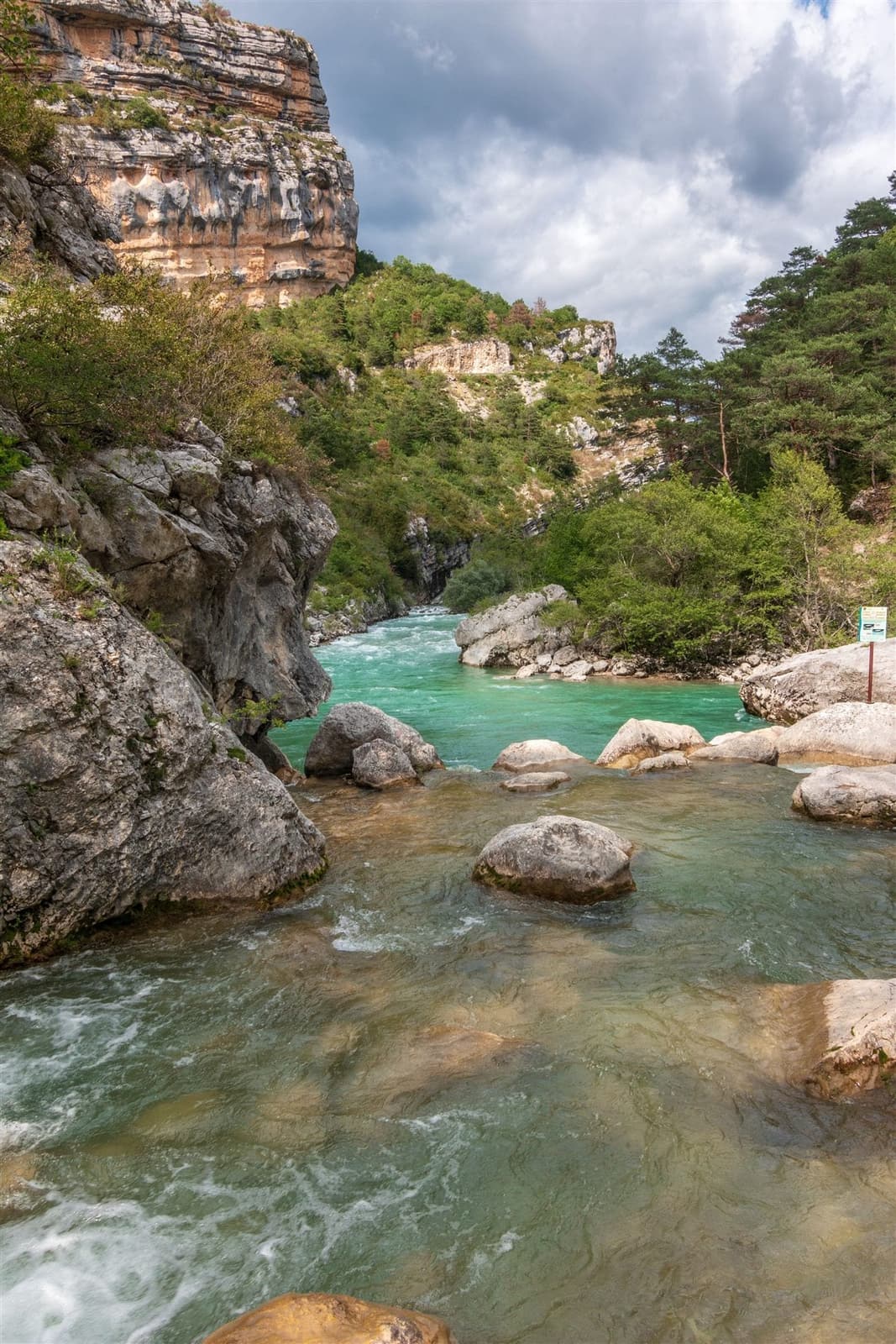 Rivière turquoise au pied d'une falaise rocheuse, dans des gorges